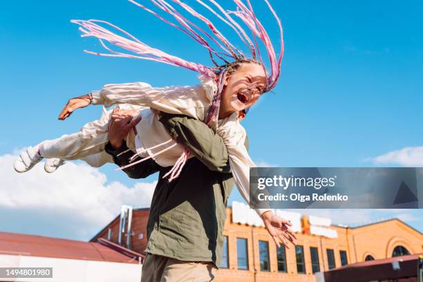 spinning girl and pure childhood fun with father. laughing and screaming little girl with pink braided hair swirling in man hands. playing together and have fun on walking - hole stock-fotos und bilder