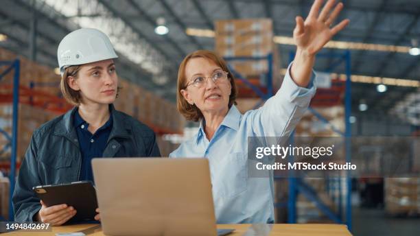 young caucasian woman worker and mature female manager checks stock inventory with tablet and laptop and discuss talk together in retail warehouse. logistic industry business. - joining the dots stock pictures, royalty-free photos & images