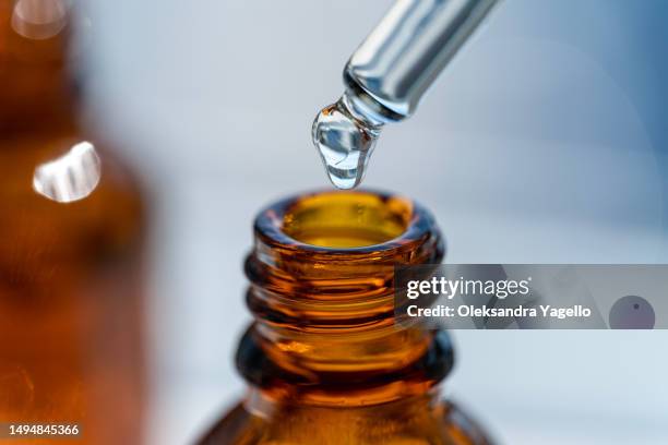 open amber bottle dropper pipette with serum or essential oil. container with cosmetic transparent liquid. - aromaterapia imagens e fotografias de stock