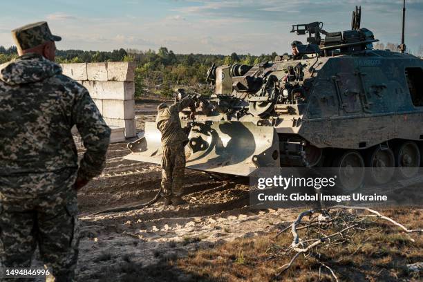 Ukrainian military members use an armored recovery vehicle Bergepanzer 3 to pull their comrades car which got stuck off-road on May 11, 2023 in...