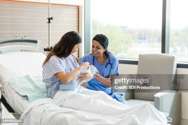 female nurse smiles while helping reassure the new mother - midwifery stock pictures, royalty-free photos & images