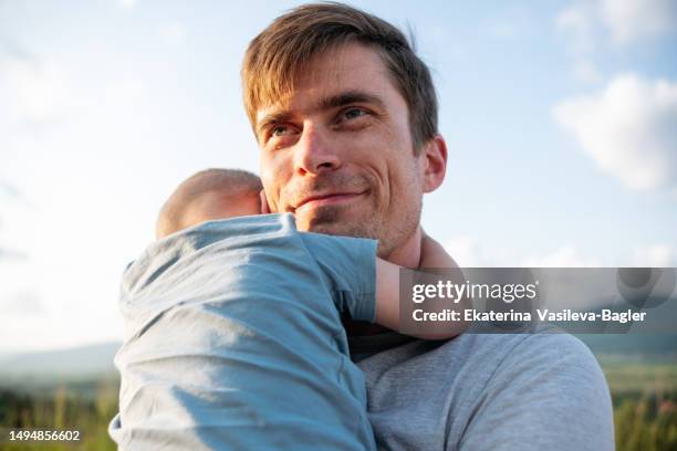 portrait of a happy father with a baby in his arms - face arms stock pictures, royalty-free photos & images