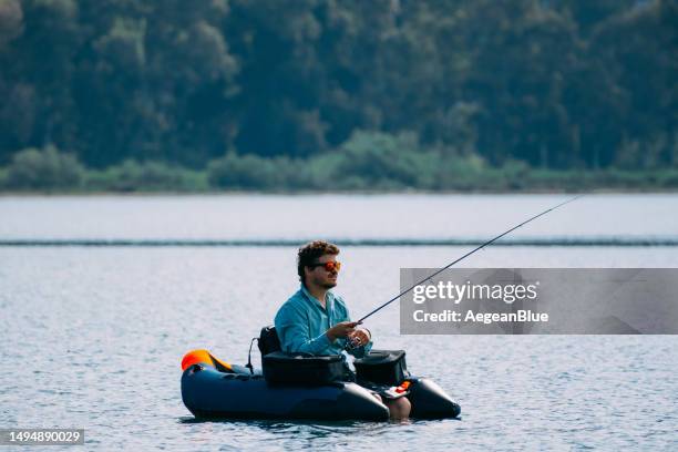 man fishing from inflatable boat - fishing rod stock pictures, royalty-free photos & images