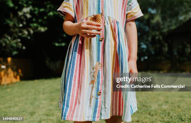 a little girl drips chocolate / vanilla ice cream all over her nice linen dress on a hot summers day - prueba de tinción fotografías e imágenes de stock