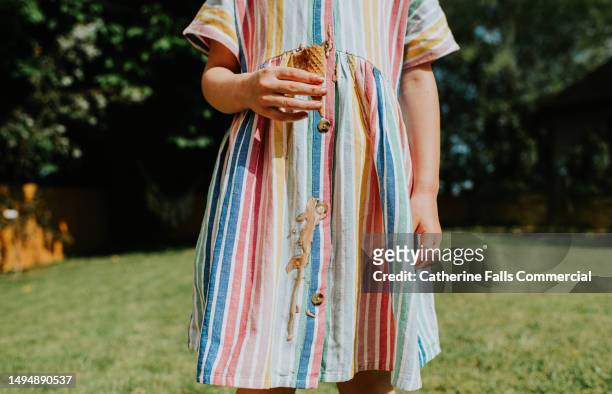 a little girl drips chocolate / vanilla ice cream all over her nice linen dress on a hot summers day - ruined clothes stock pictures, royalty-free photos & images