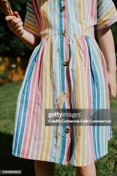 a little girl drips chocolate / vanilla ice cream all over her nice linen dress on a hot summers day - girl eating messy ice cream cone stock pictures, royalty-free photos & images