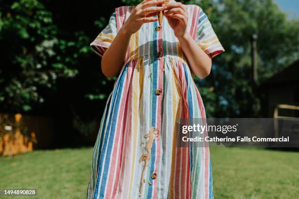 a little girl drips chocolate / vanilla ice cream all over her nice linen dress on a hot summers day - prueba de tinción fotografías e imágenes de stock