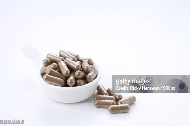 close-up of capsules in bowl over white background - ashwagandha stockfoto's en -beelden