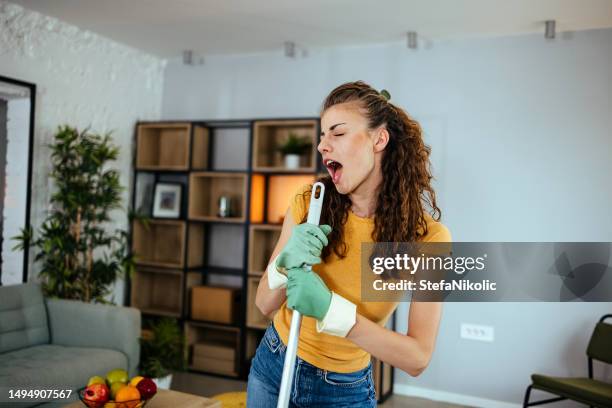 femme heureuse nettoyage maison avec lavette et de s’amuser - balai photos et images de collection
