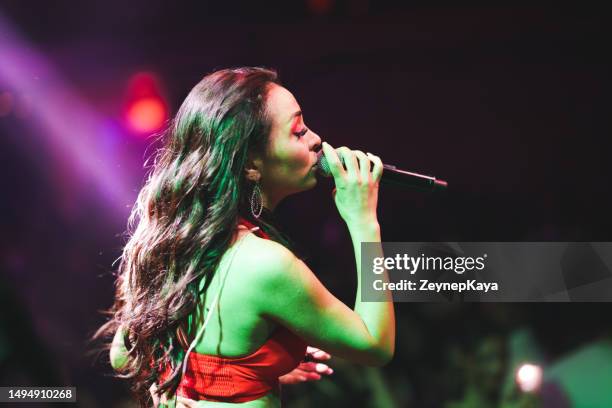 musicien sur scène chantant avec micro devant un public bondé - concert de musique pop photos et images de collection