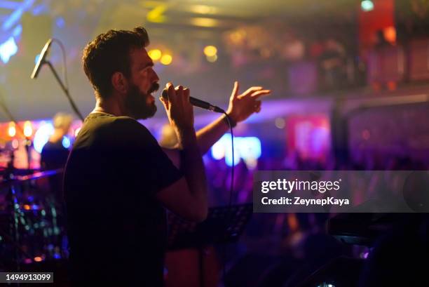 cantante masculino tocando la guitarra en el escenario - cantautor fotografías e imágenes de stock