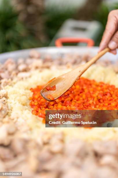 cook mixing tomato sauce to a pan with rice outdoors - multi fuel stoves stock pictures, royalty-free photos & images