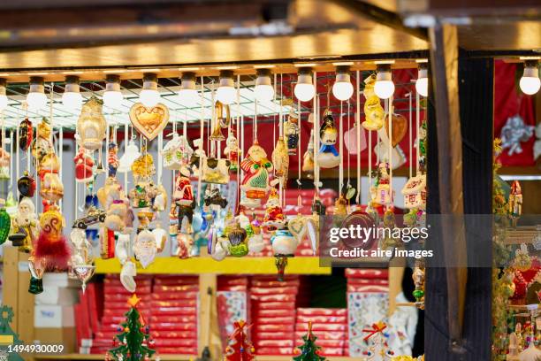 photograph of a market stall illuminated with white bulbs and filled with christmas decorations. - munich christmas stock-fotos und bilder