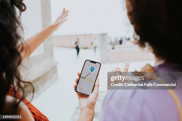 two woman discuss a walking route using an online map application - phone map stock pictures, royalty-free photos & images