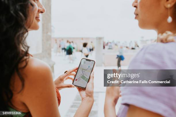 two woman discuss a walking route using an online map application - telecommunications tower stock pictures, royalty-free photos & images