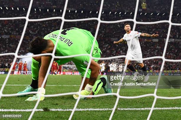 Rui Patricio of AS Roma looks dejected as Gonzalo Montiel of Sevilla FC celebrates scoring the sides winning penalty in the penalty shoot out during...