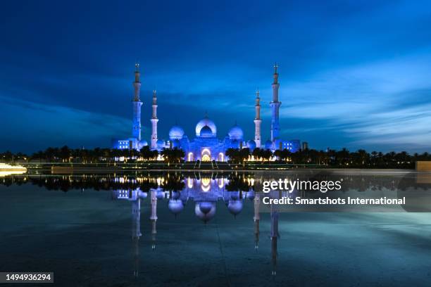 "sheikh zayed grand mosque" illuminated at dusk with perfect reflection on reflecting pool in abu dhabi, united arab emirates - sheikh zayed mosque stock-fotos und bilder