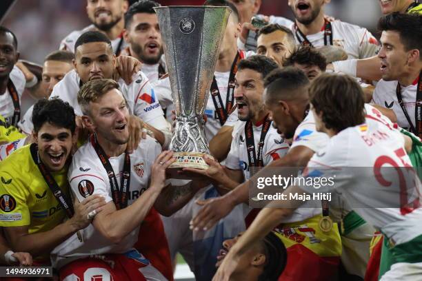 Ivan Rakitic and Jesus Navas of Sevilla FC lift the UEFA Europa League trophy after the team's victory during the UEFA Europa League 2022/23 final...