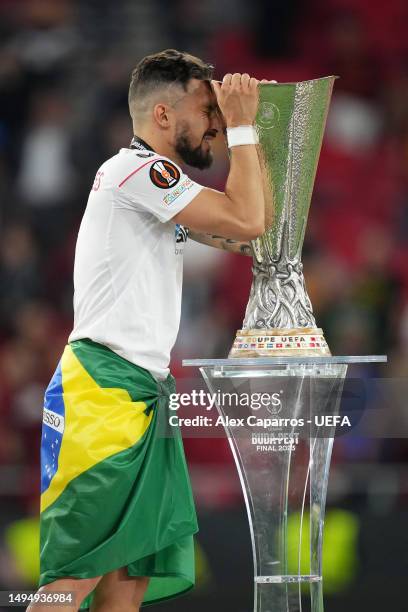 Alex Telles of Sevilla FC interacts with the UEFA Europa League trophy as they collect their winners medal after defeating AS Roma in the penalty...