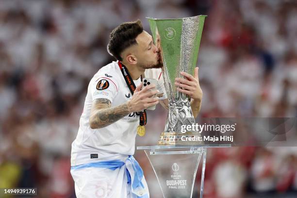 Lucas Ocampos of Sevilla FC kisses the UEFA Europa League trophy after the team's victory as they film a selfie on their mobile phone during the UEFA...
