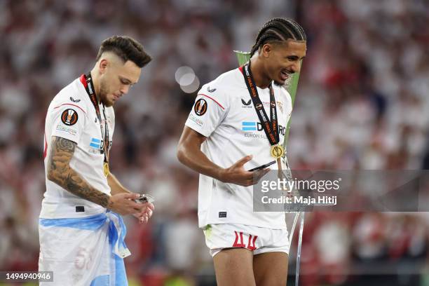 Lucas Ocampos and Loic Bade of Sevilla FC look on as they pass the UEFA Europa League Trophy after collecting their winners medals during the UEFA...
