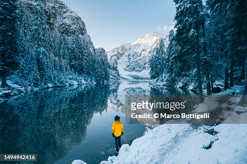 Man admiring a mountain lake in winter scenery