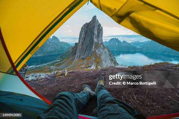 personal perspective of person relaxing in a tent looking at sunset on mountain top, senja, norway - shoes top view stockfoto's en -beelden