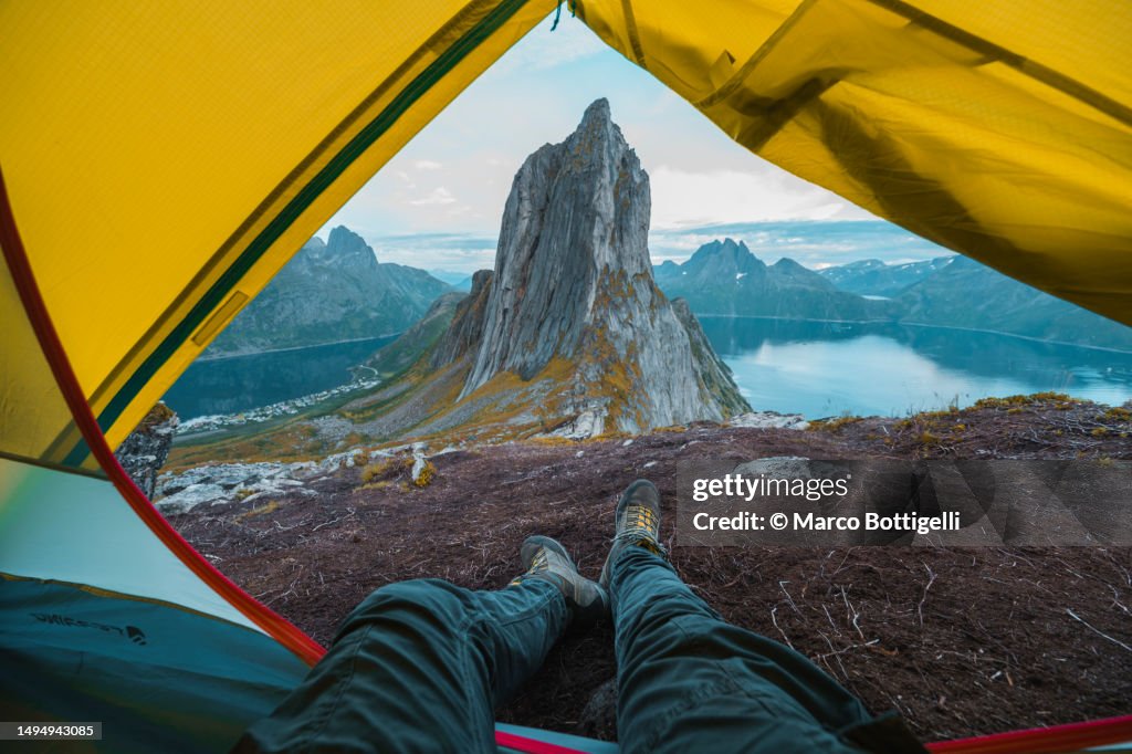 Personal perspective of person relaxing in a tent looking at sunset on mountain top, Senja, Norway