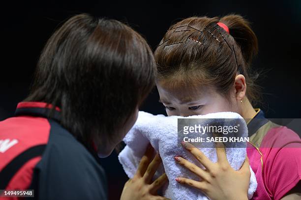 Ai Fukuhara of Japan listens to her coach while playing against Anna Tikhomirova of Russia during a table tennis women's singles round match of the...