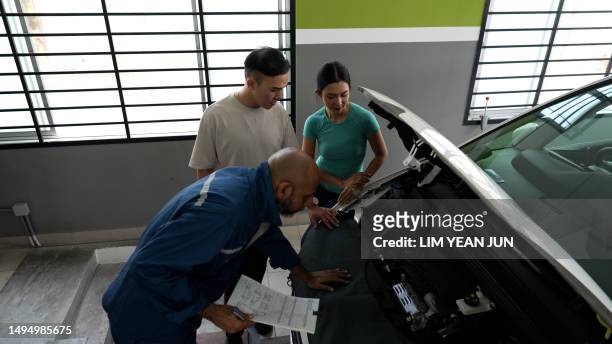 asian auto mechanic conductin vehicle diagnostic for service for asian couple - asian couple garage car stock pictures, royalty-free photos & images