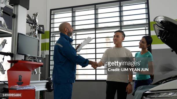 asian auto mechanic shaking hands with asian couple for completion of vehicle services - asian couple garage car stock pictures, royalty-free photos & images