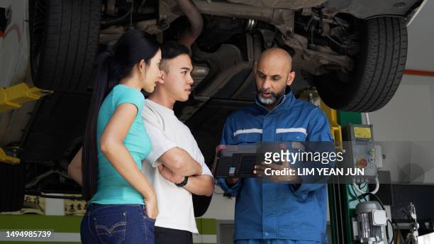 asian auto mechanic explaining car services done to asian couple - asian couple garage car stock pictures, royalty-free photos & images