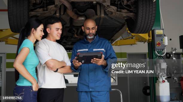 asian auto mechanic explaining car services done to asian couple - asian couple garage car stock pictures, royalty-free photos & images