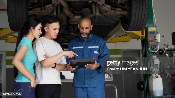 asian auto mechanic explaining car services done to asian couple - asian couple garage car stock pictures, royalty-free photos & images