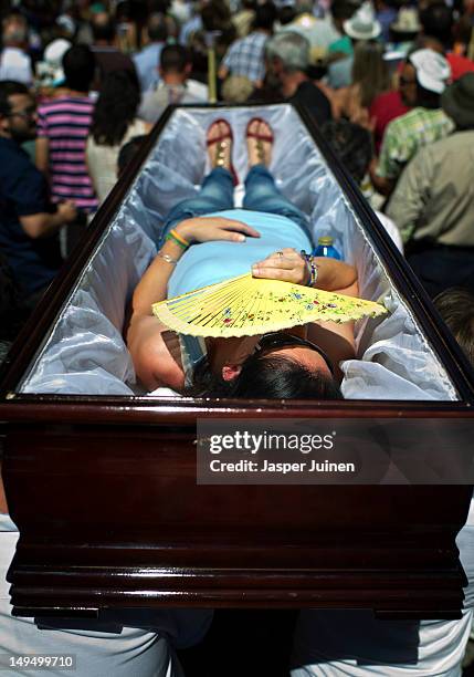 Emilia covers her face for the sun with an abanico while she is carried in a coffin taking part in a procession to keep a promise made for her father...