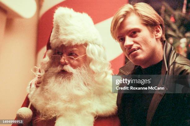 Irish American actor and comedian Denis Leary poses in front of a Christmas tree with Santa Claus on the set of the Nike "Deion Sanderclaus"...