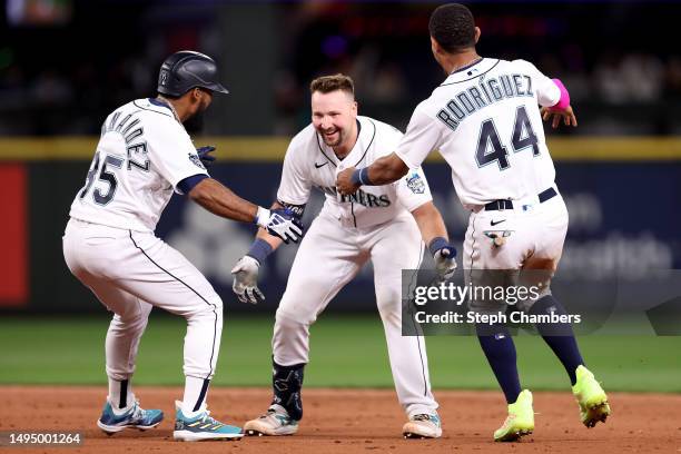 Cal Raleigh of the Seattle Mariners celebrates his walk-off single with Teoscar Hernandez and Julio Rodriguez during the tenth inning against the New...