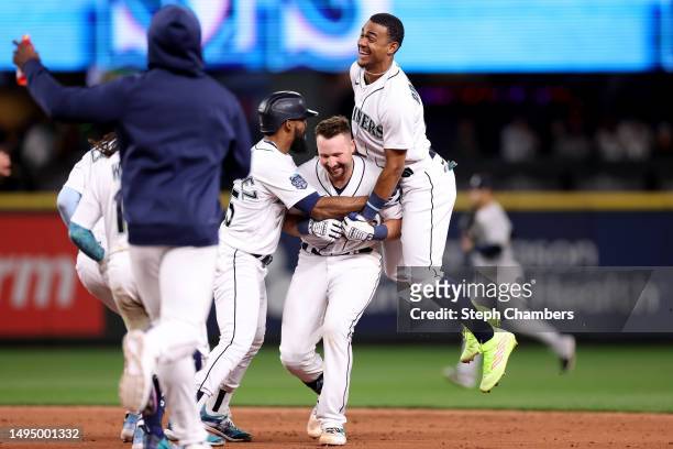 Cal Raleigh of the Seattle Mariners celebrates his walk-off single with Teoscar Hernandez and Julio Rodriguez during the tenth inning against the New...