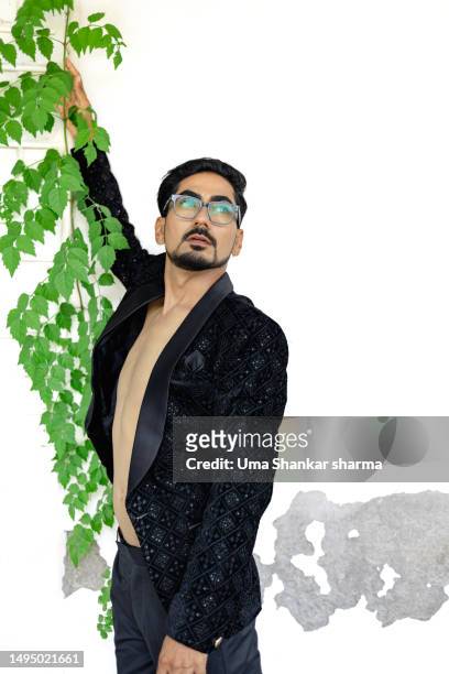 fashionable man posing against a white wall with vine plant. - camicia di paillette foto e immagini stock