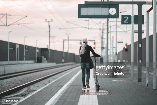 femme avec scooter sur le quai de la gare, vue arrière - quai de gare photos et images de collection