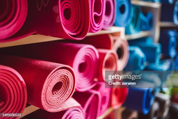 tapetes de ioga cor-de-rosa enrolados nas prateleiras do estúdio - tatame equipamento para exercícios - fotografias e filmes do acervo