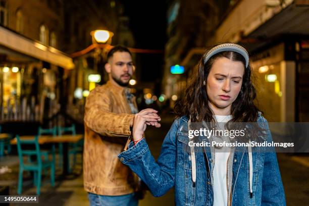 young couple argues on crowded promenade - friendship breakup stock pictures, royalty-free photos & images