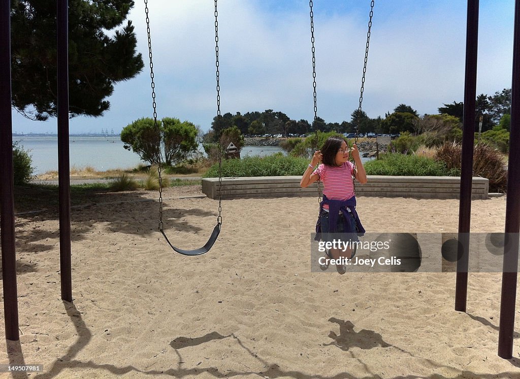 Asian child on swing on beach