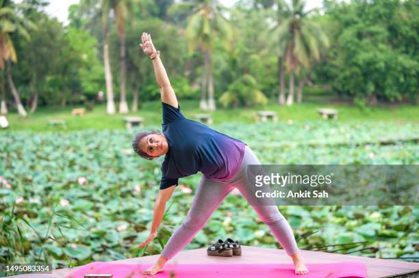 woman practicing parivrtta trikonasana or triangle pose yoga - revolved triangle pose stock pictures, royalty-free photos & images