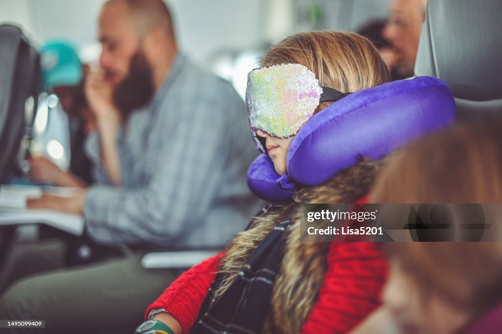 Une fille utilise un oreiller pour le cou et un masque pour les yeux pour dormir lorsqu’elle voyage en avion