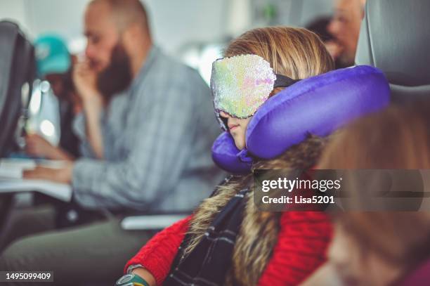 girl uses a neck pillow and eye mask to sleep while traveling on an airplane - neck pillow eye mask stock pictures, royalty-free photos & images