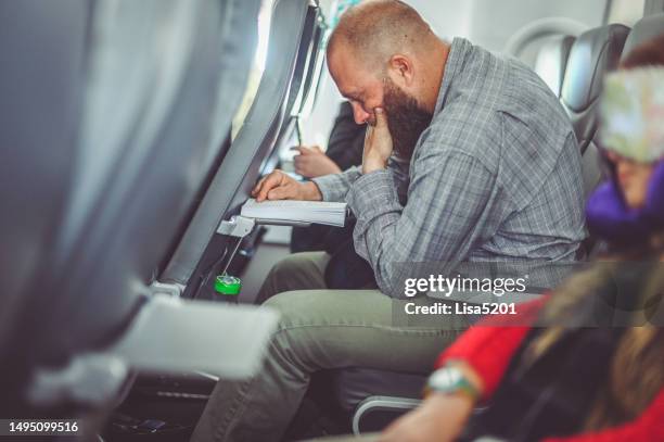 man on an airplane reading or working with tray table down - airplane tray table stock pictures, royalty-free photos & images