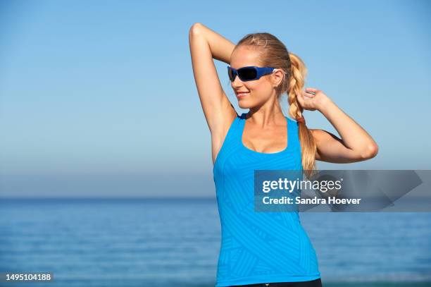 enjoying the sun while stretching after jogging on cape town beach wearing sunglasses - sonnenschutz stock pictures, royalty-free photos & images