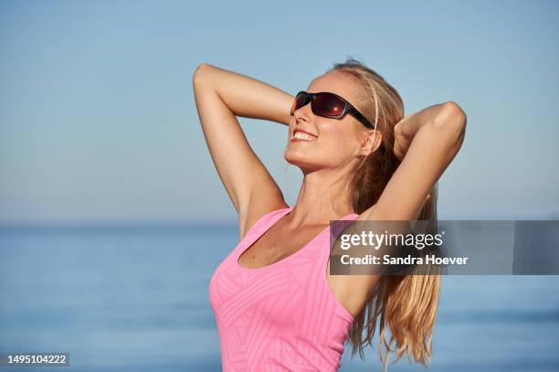 stretching exercise after jogging on cape town beach wearing sunglasses - sonnenschutz stock pictures, royalty-free photos & images
