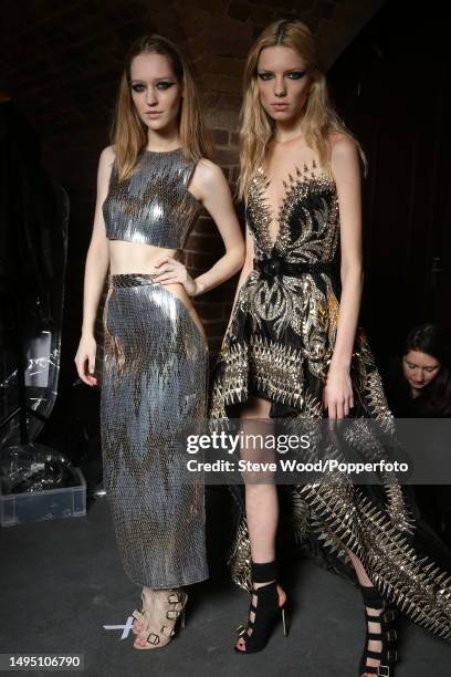 Backstage at the Julien Macdonald show during London Fashion Week Autumn/Winter 2016/17, one model wears a crop top and matching long pencil skirt in...